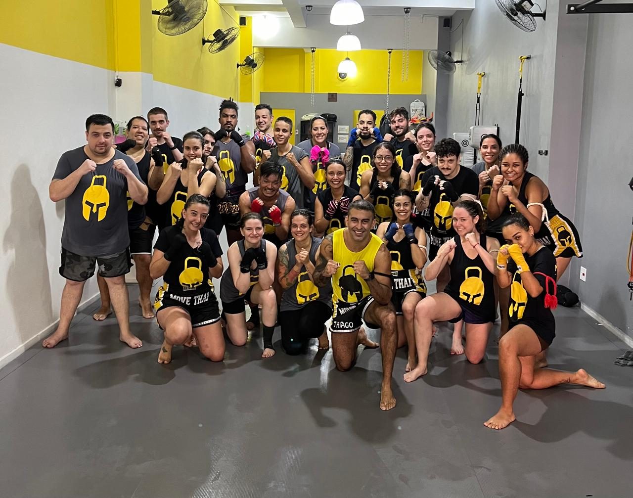 Turma do Studio Move Thai reunida no tatame, todos de punhos erguidos